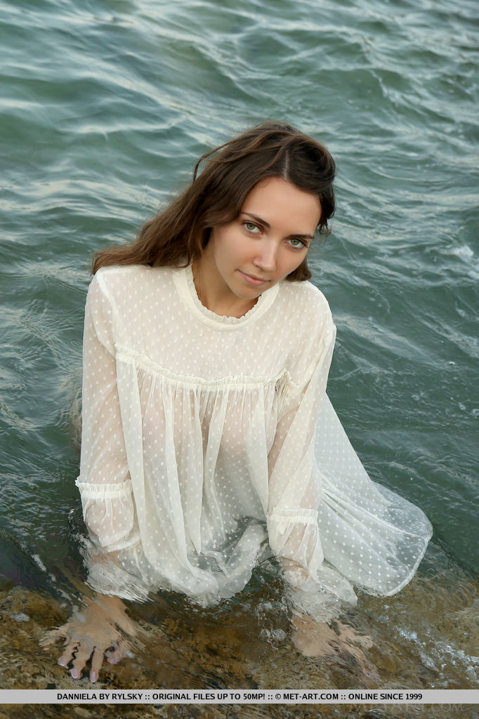 Danniela looks regal as she wears a while lace top. She dips her body into the sea and poses around the rocky shore.