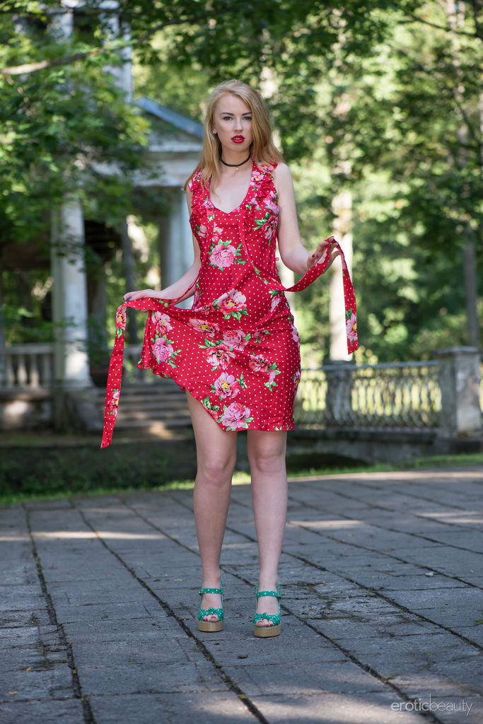 Helene is outdoors and wearing a red floral dress and bright red lipstick. She goes nude and poses around an abandoned structure. 